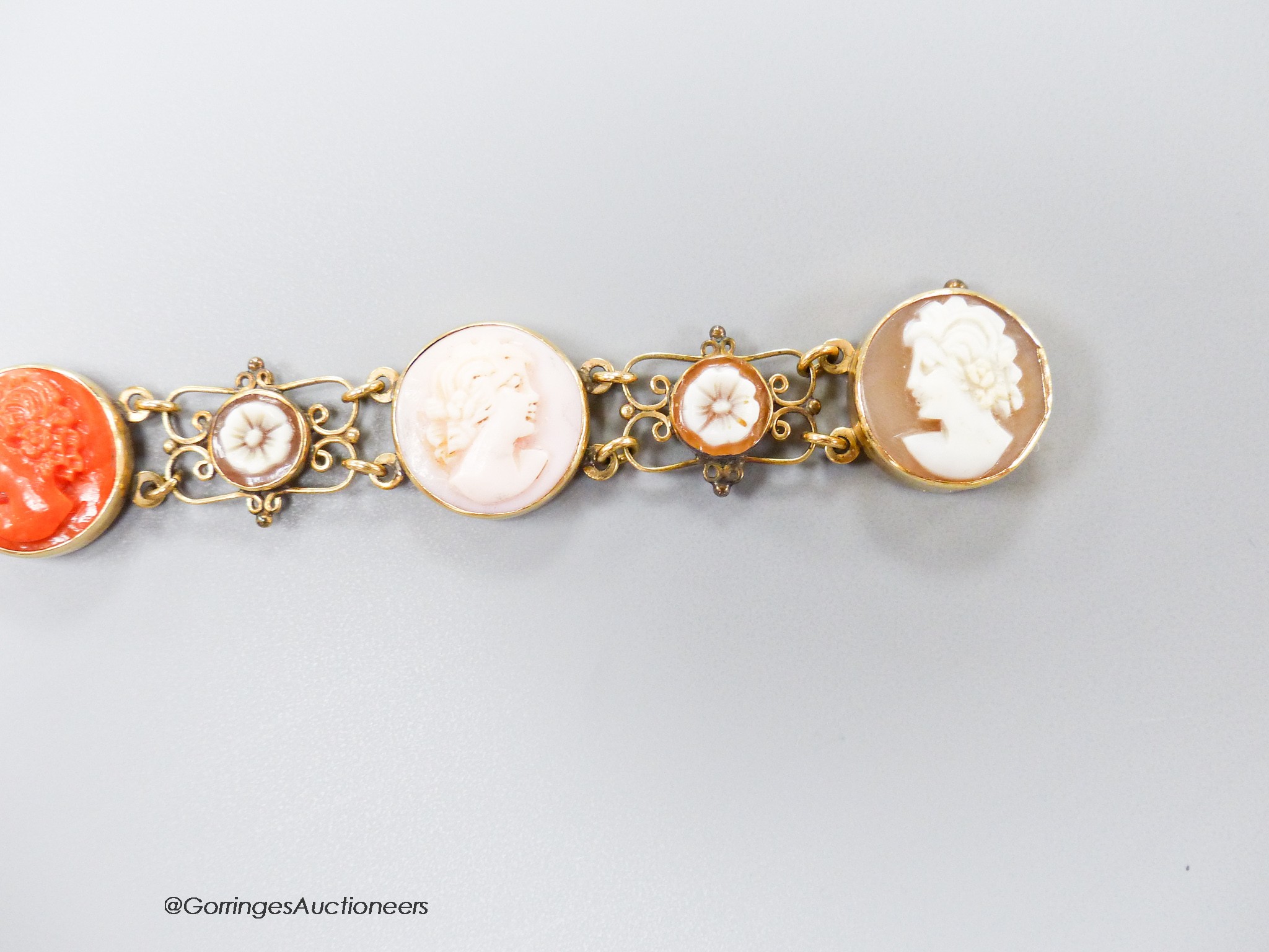 A 14k yellow metal, multi carved cameo and flowerhead set bracelet, including paua shell, shell and coral, carved with the busts of ladies, to dexter and sinister, 16.5cm, gross weight 13.5 grams.